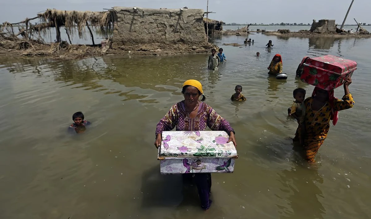 Women carry belongings salvaged from their flooded home after monsoon rains, in the Qambar Shahdadkot district of Sindh Province, of Pakistan, on September 6, 2022. (AP/File)