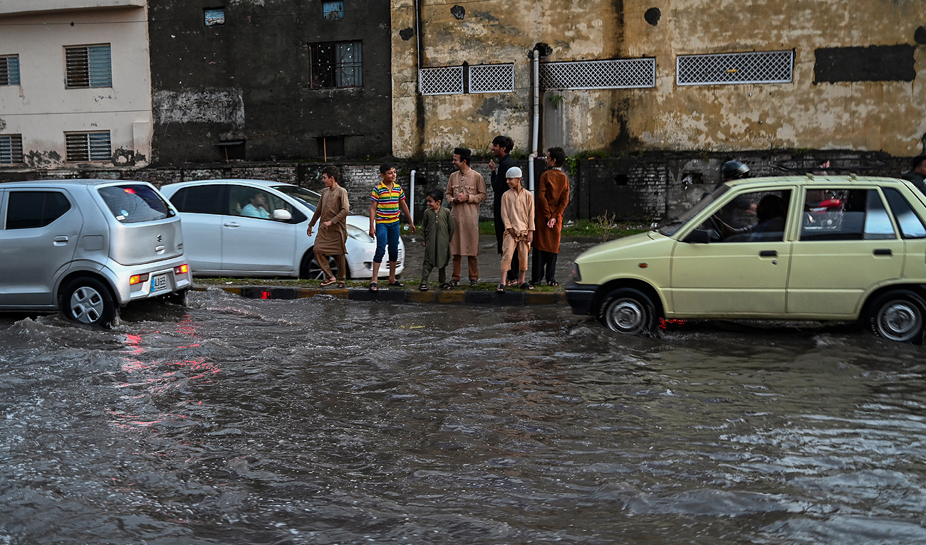 In this file photo, taken on September 20, 2021, children stand in a pavement next to a flooded street after a rainfall in Rawalpindi. (AFP/File)