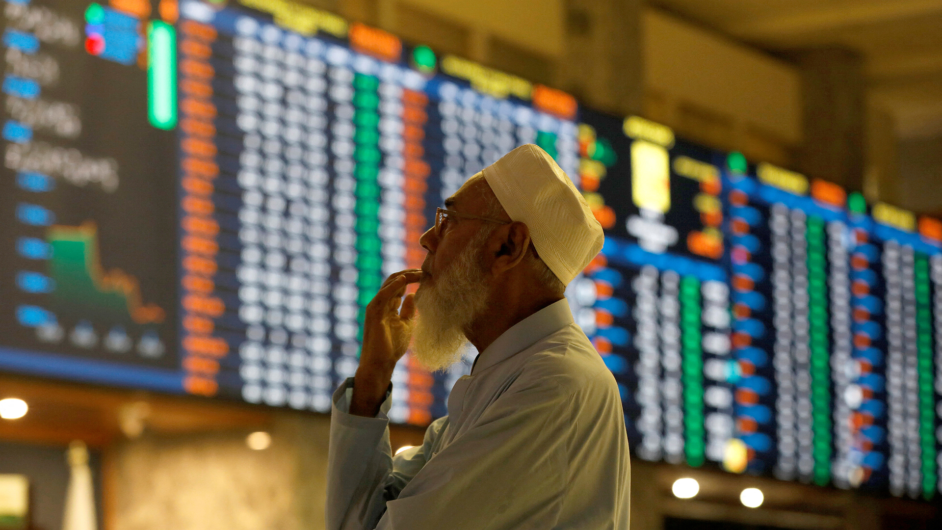 A stock broker reacts while monitoring the market on the electronic board displaying share prices during trading session at the Pakistan Stock Exchange, in Karachi, Pakistan July 3, 2023. (REUTERS)