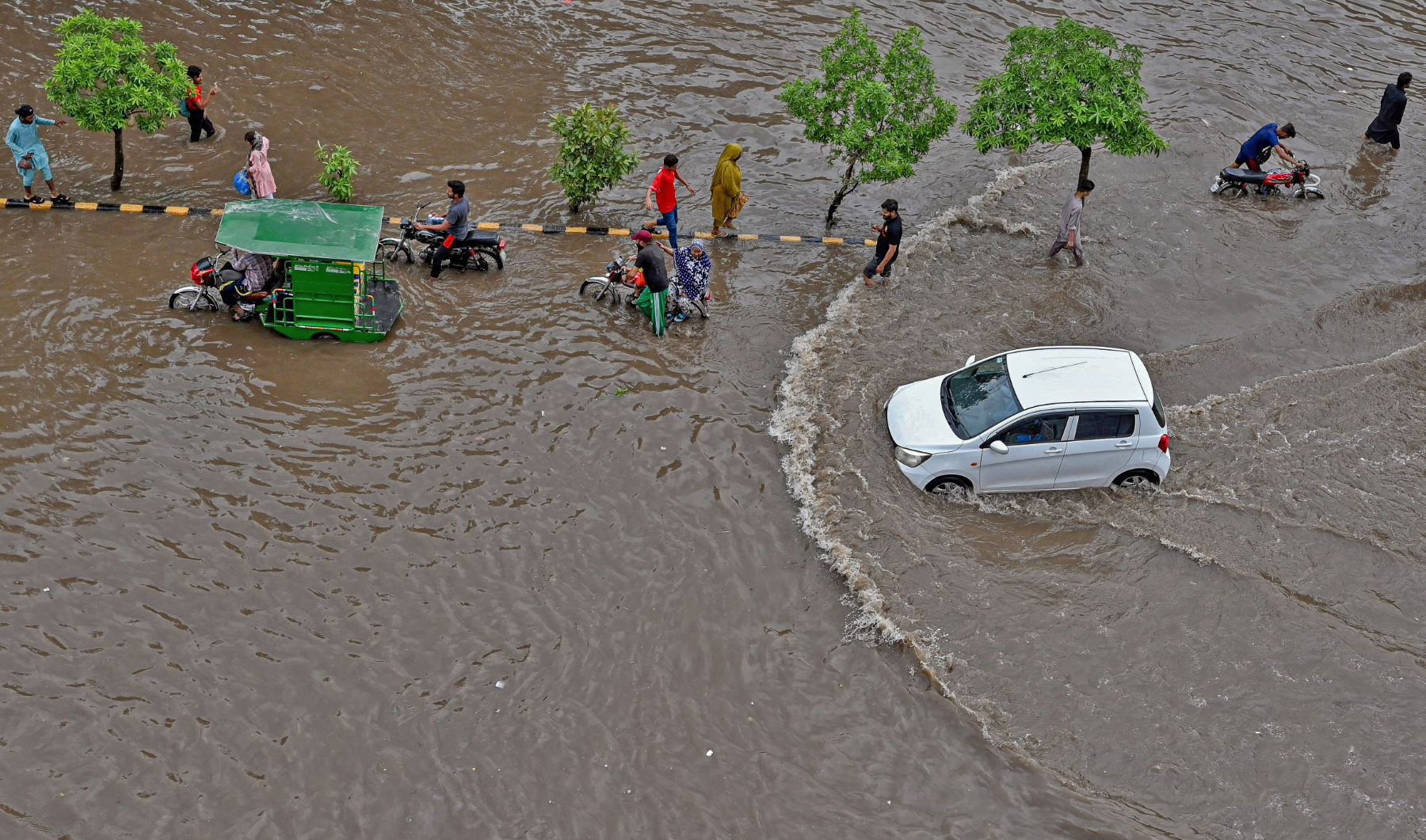 People make their way through a waterlogged road after a heavy rainfall in Lahore on June 26, 2023. (AFP)