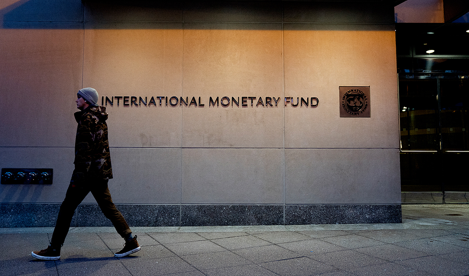 A pedestrian walks past the International Monetary Fund (IMF) headquarters in Washington DC, United States on January 10, 2022. (AFP/File)