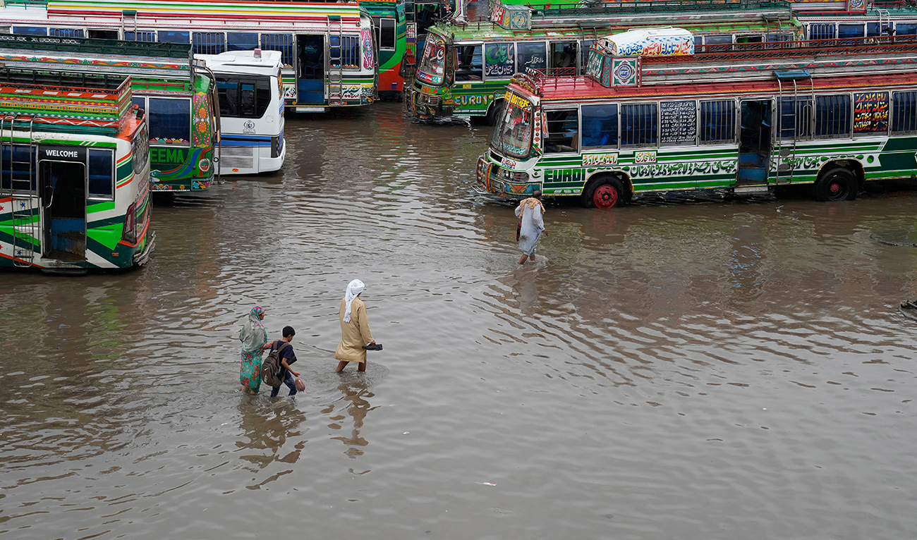 Passengers wade through a flooded bus terminal caused by heavy monsoon rainfall in Lahore, Pakistan, Wednesday, July 5, 2023. Officials say heavy monsoon rains have lashed across Pakistan, killing a number of people. (AP)