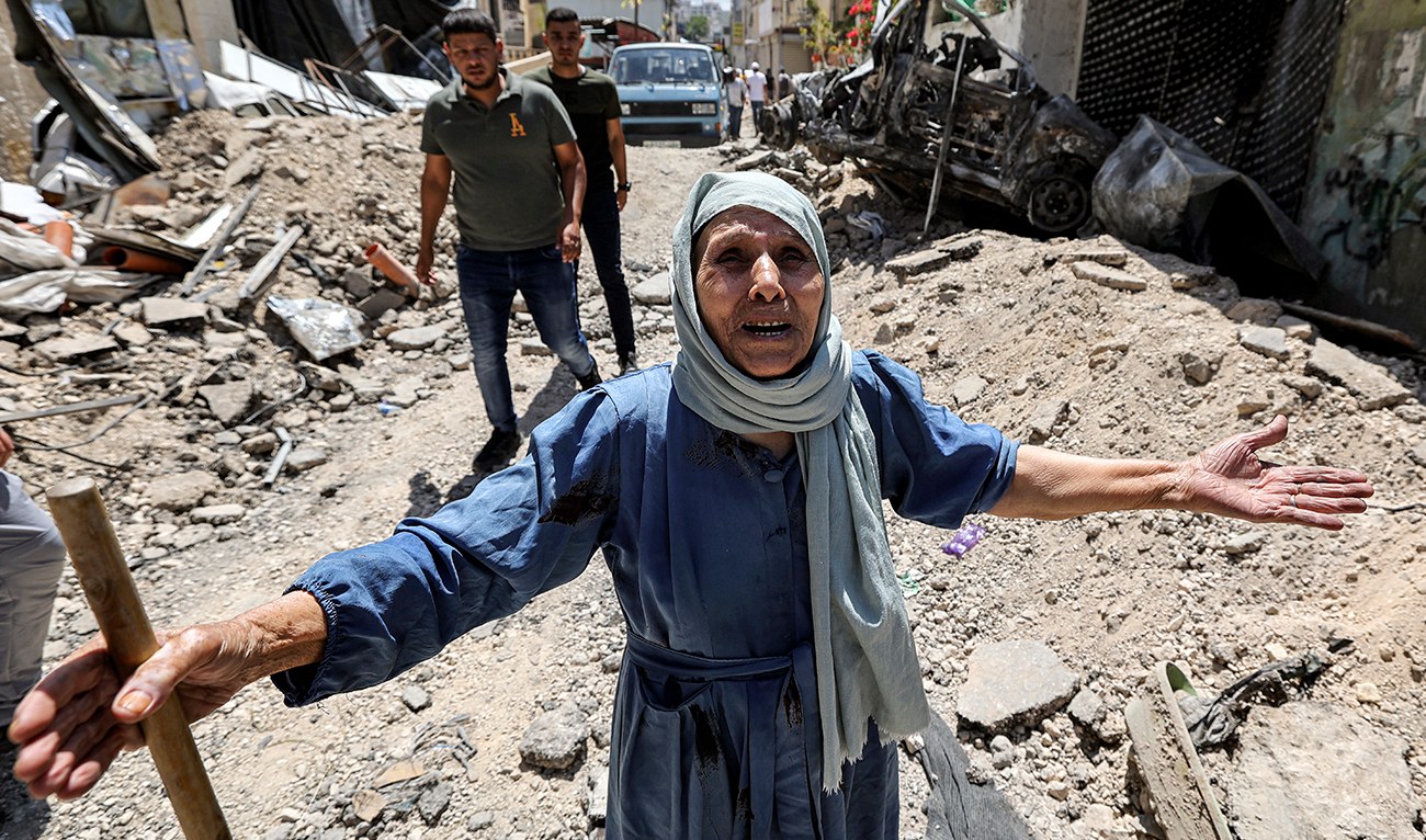 An elderly woman reacts as she stands by the rubble of broken pavement along an alley in Jenin in the occupied West Bank on July 5, 2023, after the Israeli army declared the end of a two-day military operation in the area. (AFP)