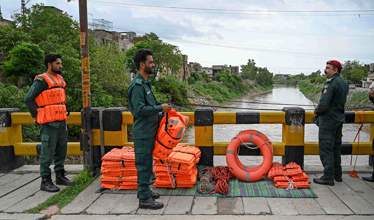 Rescue workers monitor the flood situation at a bridge over a stream in Rawalpindi, Pakistan, on July 7, 2023. (AFP)