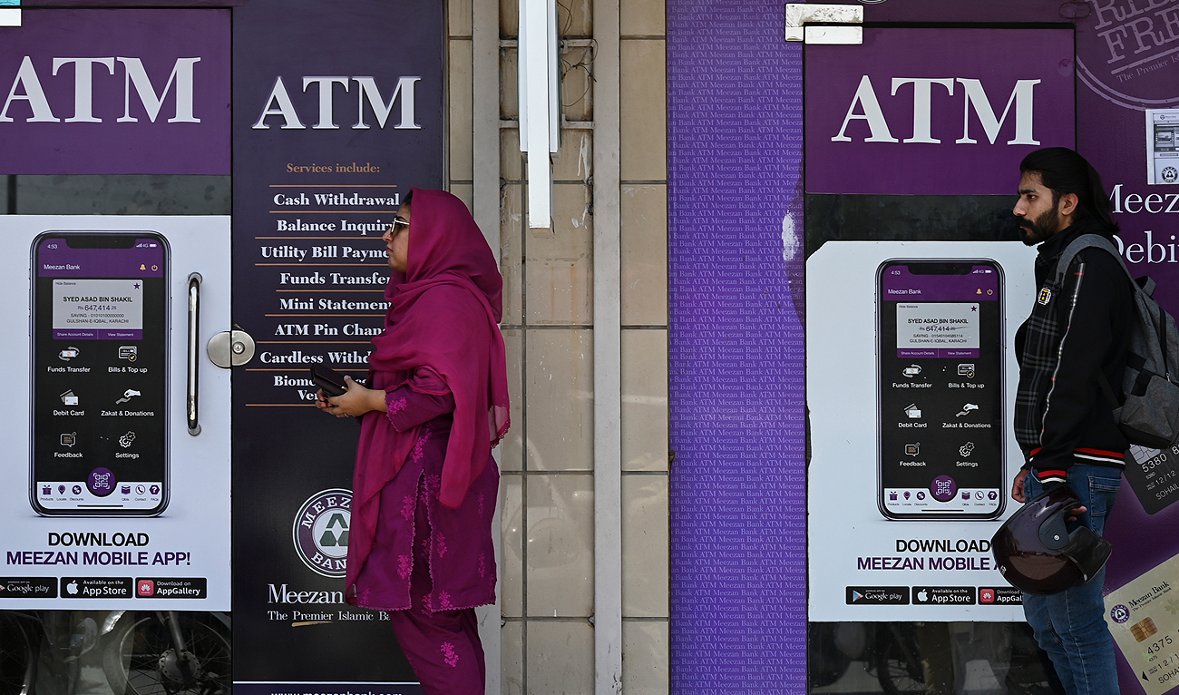People queue along a street to use an ATM bank machine in Rawalpindi on June 9, 2023. (AFP/File)