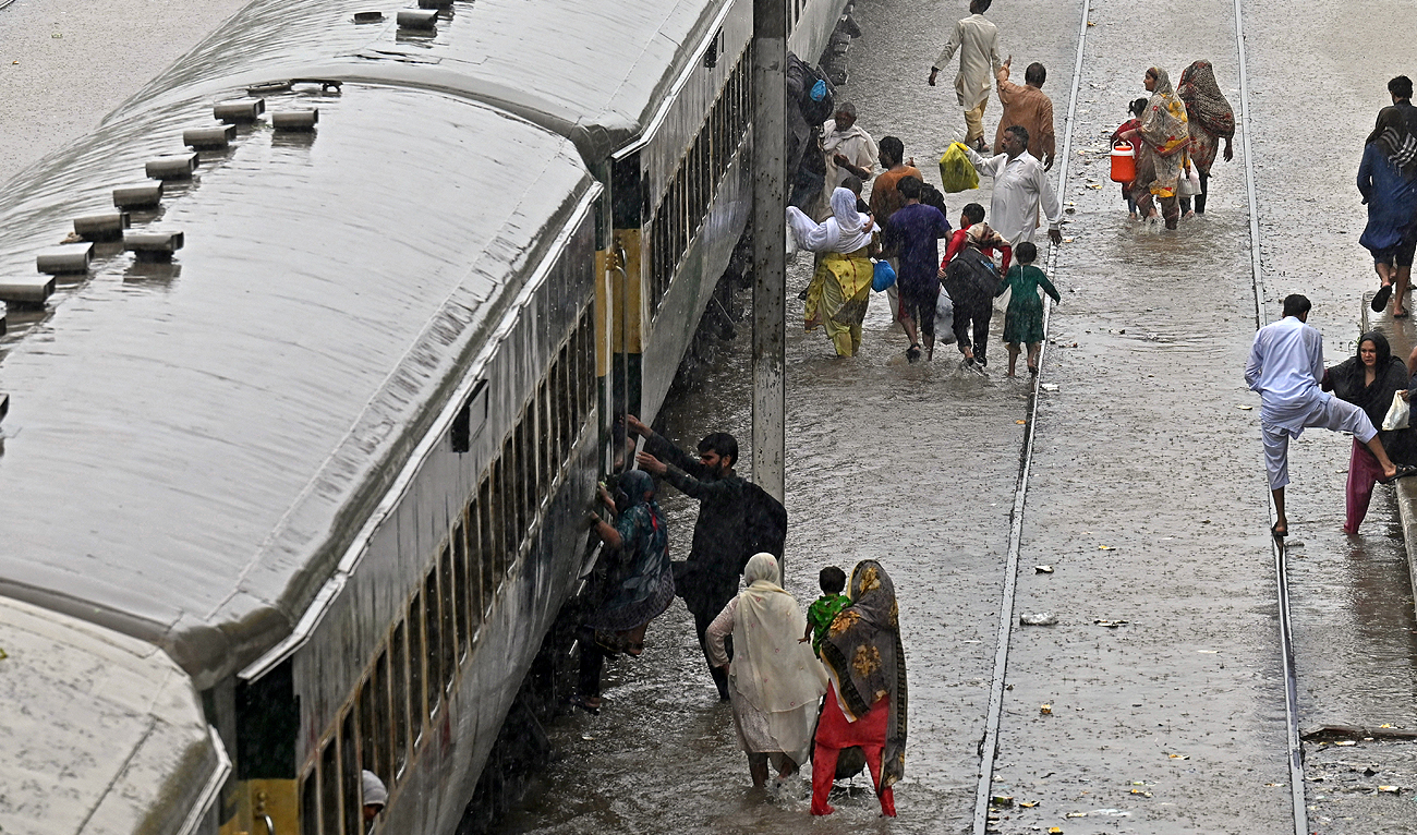 Passengers board a train at a flooded railway station after heavy rainfall in Lahore on July 5, 2023. (AFP)