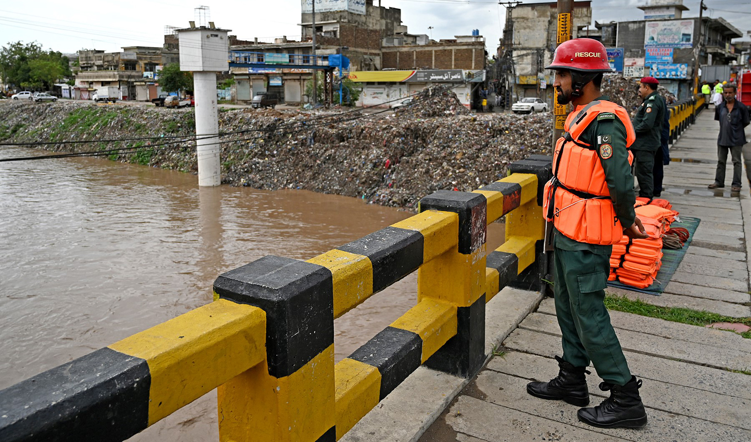 Rescue workers monitor the flood situation at a bridge over a stream in Rawalpindi, Pakistan, on July 7, 2023. (AFP)