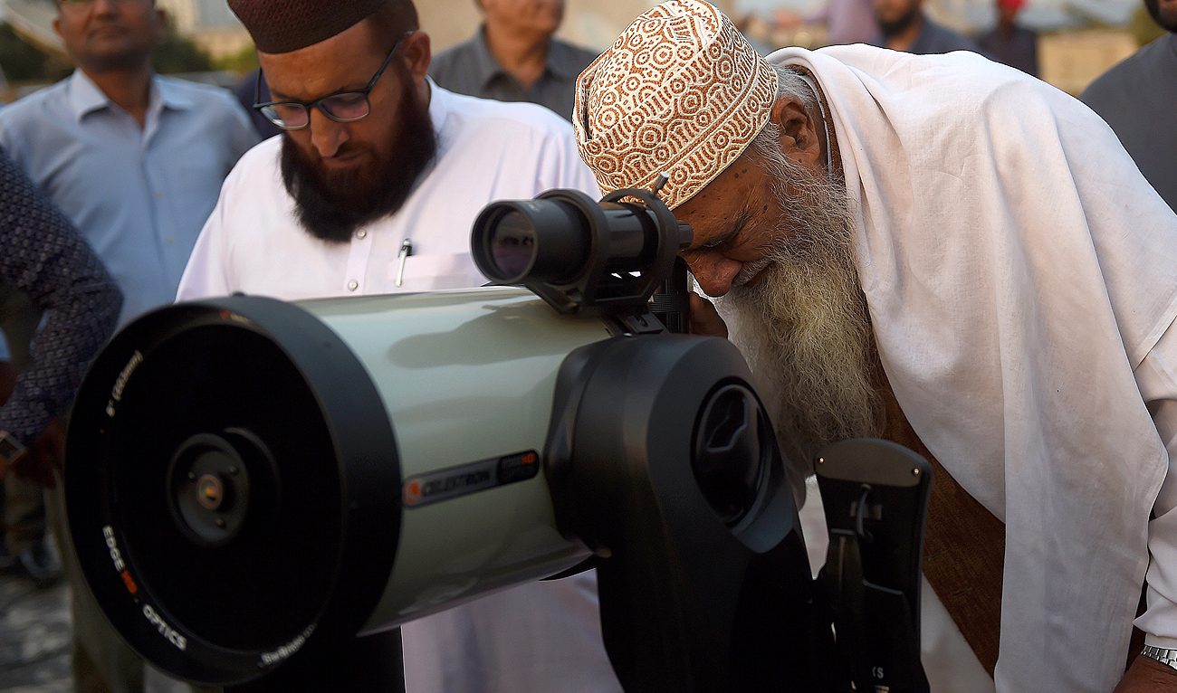 In this photo, taken on March 22, 2023, a member of Pakistan's Ramadan moon-sighting committee uses a telescope to observe the appearance of the Ramadan Moon in Karachi. (AFP/File)