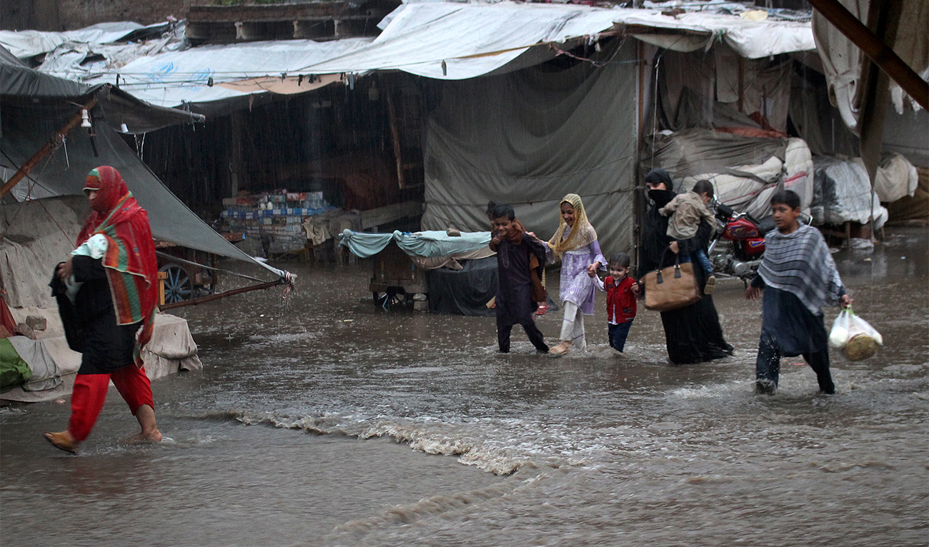 Women and children walk on a road during heavy rainfall, in Peshawar, Pakistan, on July 15, 2023. (AP)