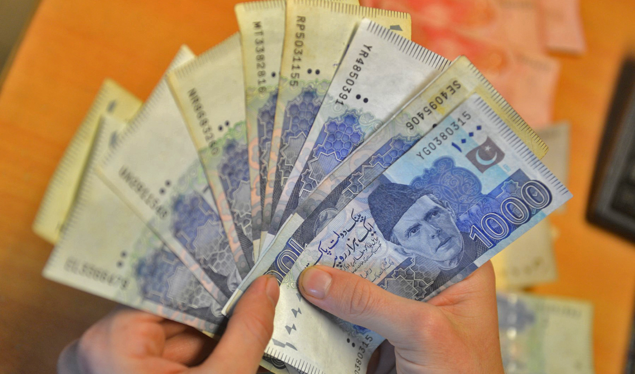 A money changer counts Pakistan's currency at a market in Karachi on January 6, 2023. (AFP/File)
