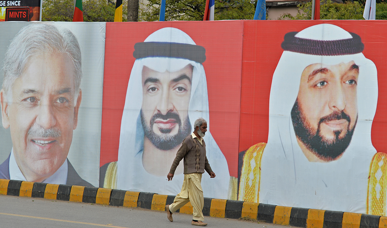 A worker walks past portraits of UAE President Sheikh Mohamed bin Zayed al-Nahyan (C) and Pakistan Prime Minister Nawaz Sharif (L) along the constitution avenue in Islamabad on January 29, 2023. (AFP/File)