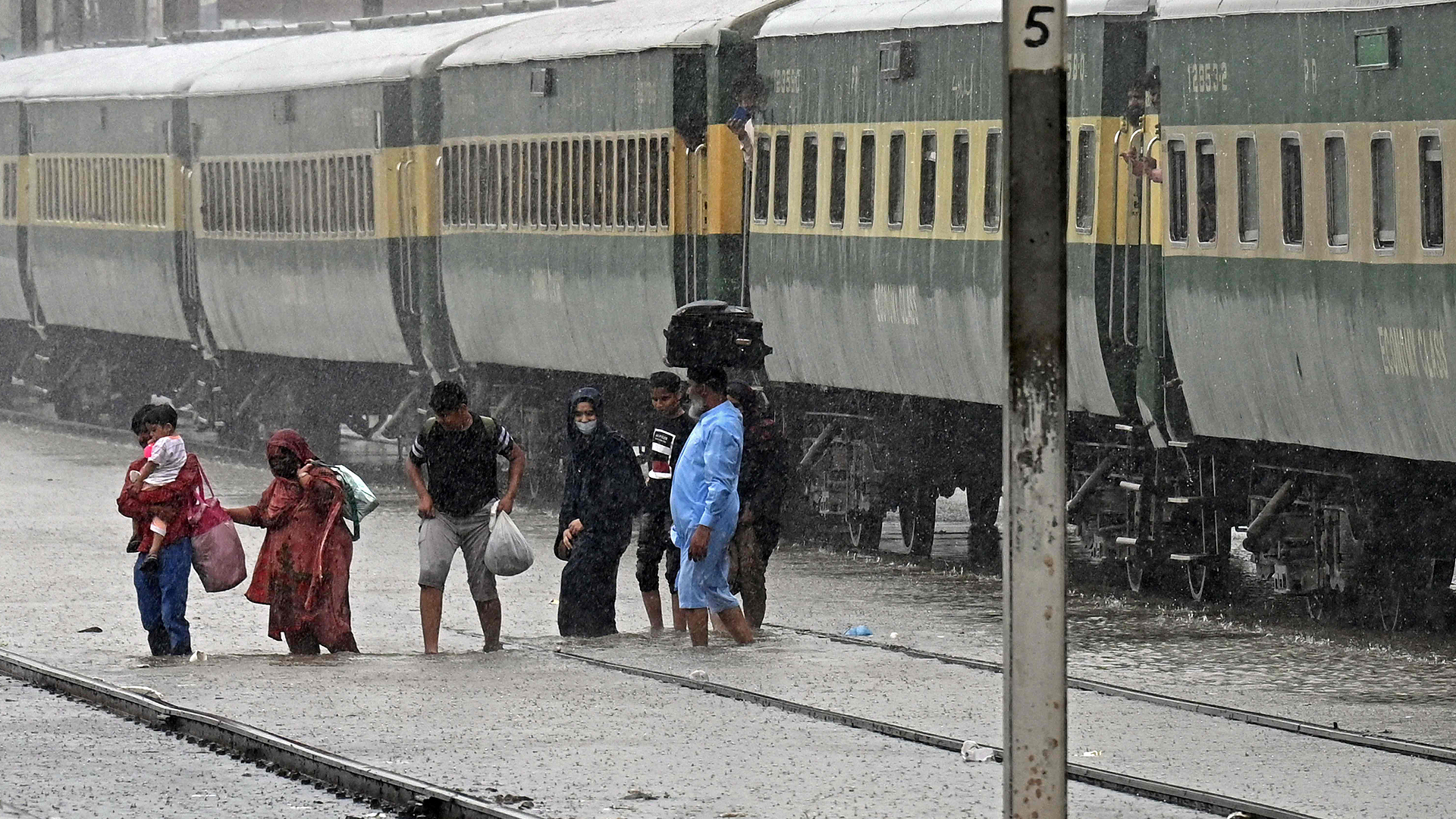 Passengers disembark from a train at a flooded railway station after heavy rainfall in Lahore on July 5, 2023. (AFP)