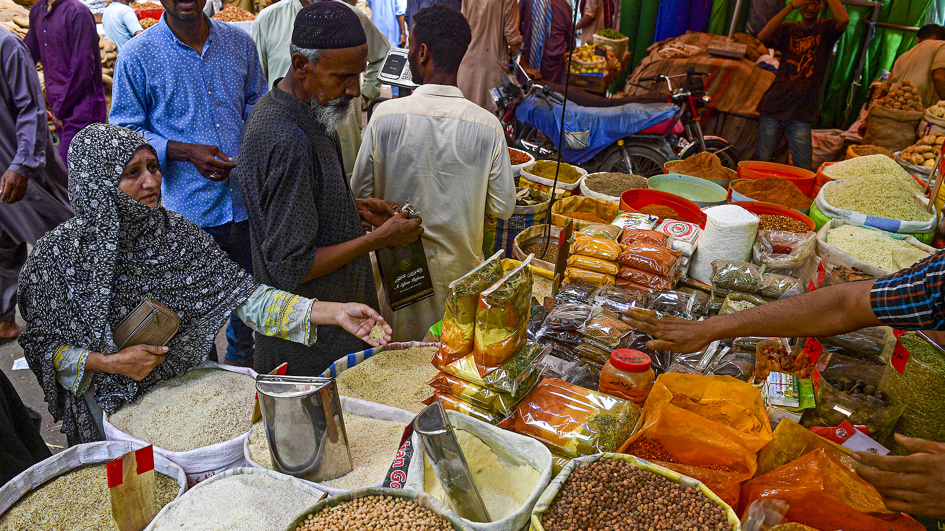Customers bargain as they buy cereals and legumes at a shop in Karachi on June 8, 2023. (AFP/File)