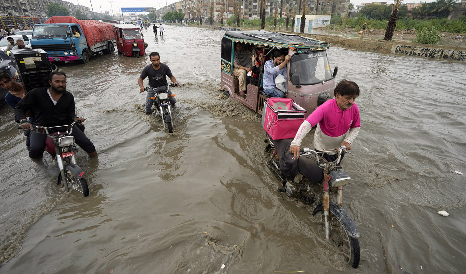Motorcyclists drive through a flooded road caused by heavy monsoon rainfall in Karachi, Pakistan, on July 24, 2023. (AP)
