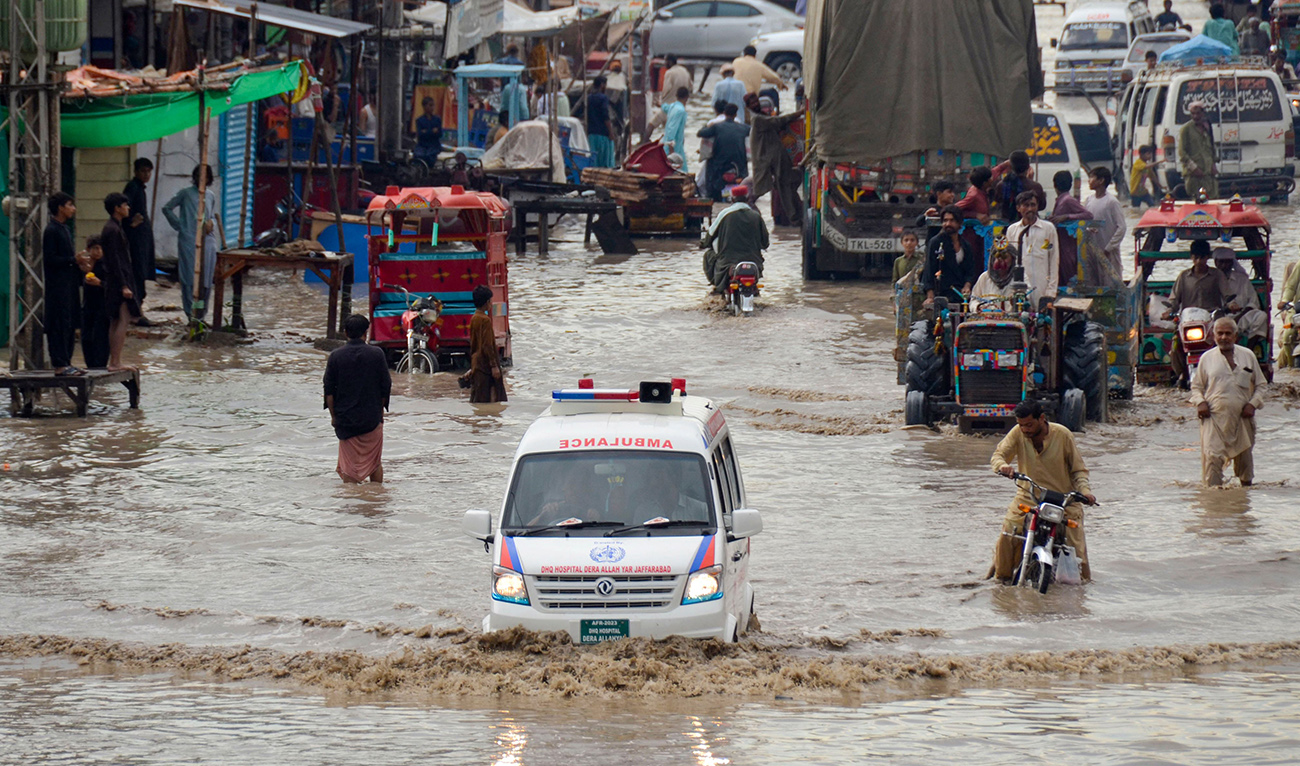 Commuters wade through a flooded street after heavy monsoon rains in Jaffarabad district of Balochistan province on July 27, 2023. Hundreds of people were displaced when at least 50 villages were inundated after the Chenab River burst its banks in Pakistan's Punjab province, officials said on July 27. (AFP/File)