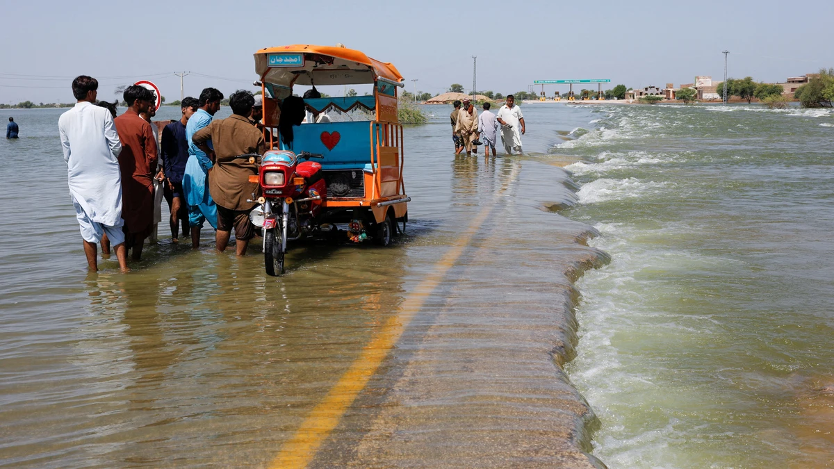 In this file photo, taken on September 16, 2022, displaced people stand on flooded highway, following rains and floods during the monsoon season in Sehwan, Pakistan. (REUTERS/File)