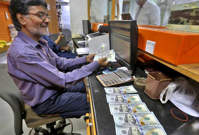 A Pakistani money trader counts U.S. dollars for a customer at a currency exchange office, in Karachi, Pakistan, on May 19, 2022. (AP/File)