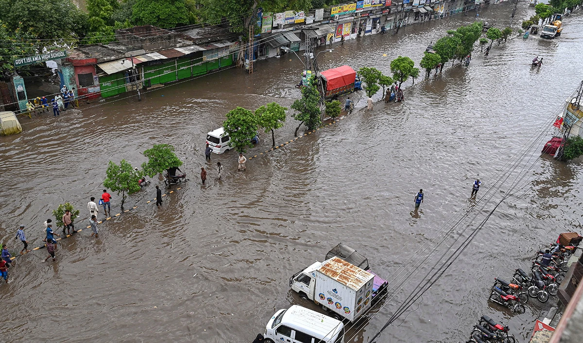 People make their way through a waterlogged road after a heavy rainfall in Lahore on June 26, 2023. (AFP/File)