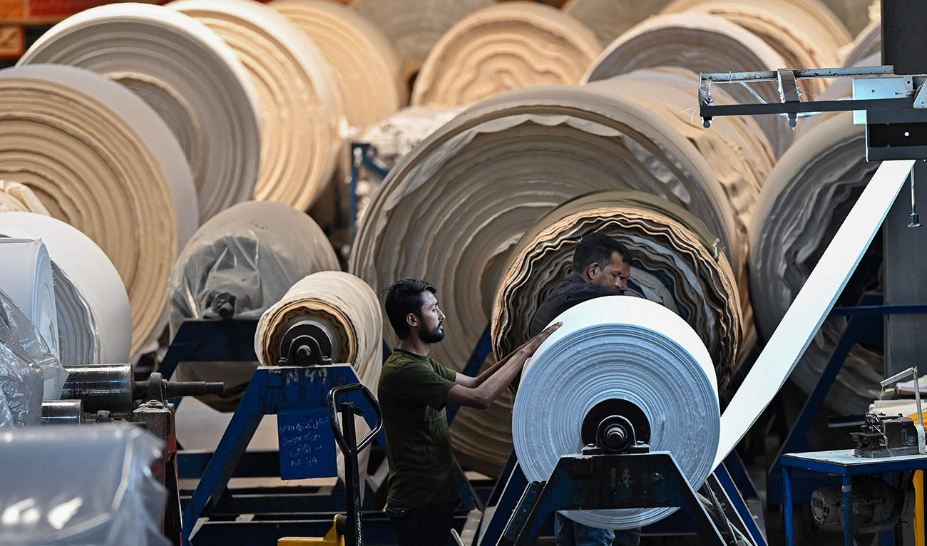 In this picture taken on July 20, 2023, a worker operates a machine preparing fabric at the Kohinoor Textile Mills in Lahore. (AFP/File)