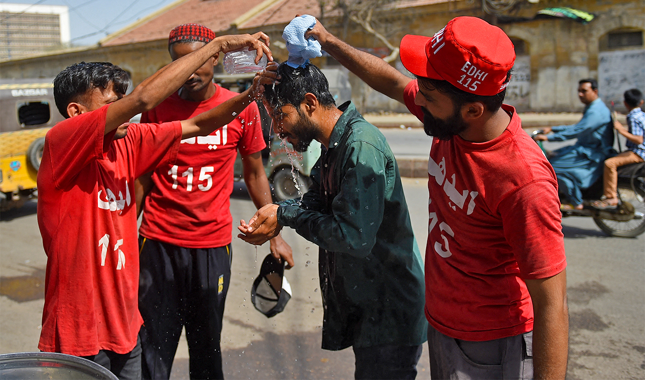 Volunteers of Edhi Foundation cool down a man with water during a hot day in Karachi on April 11, 2021. (AFP/File)