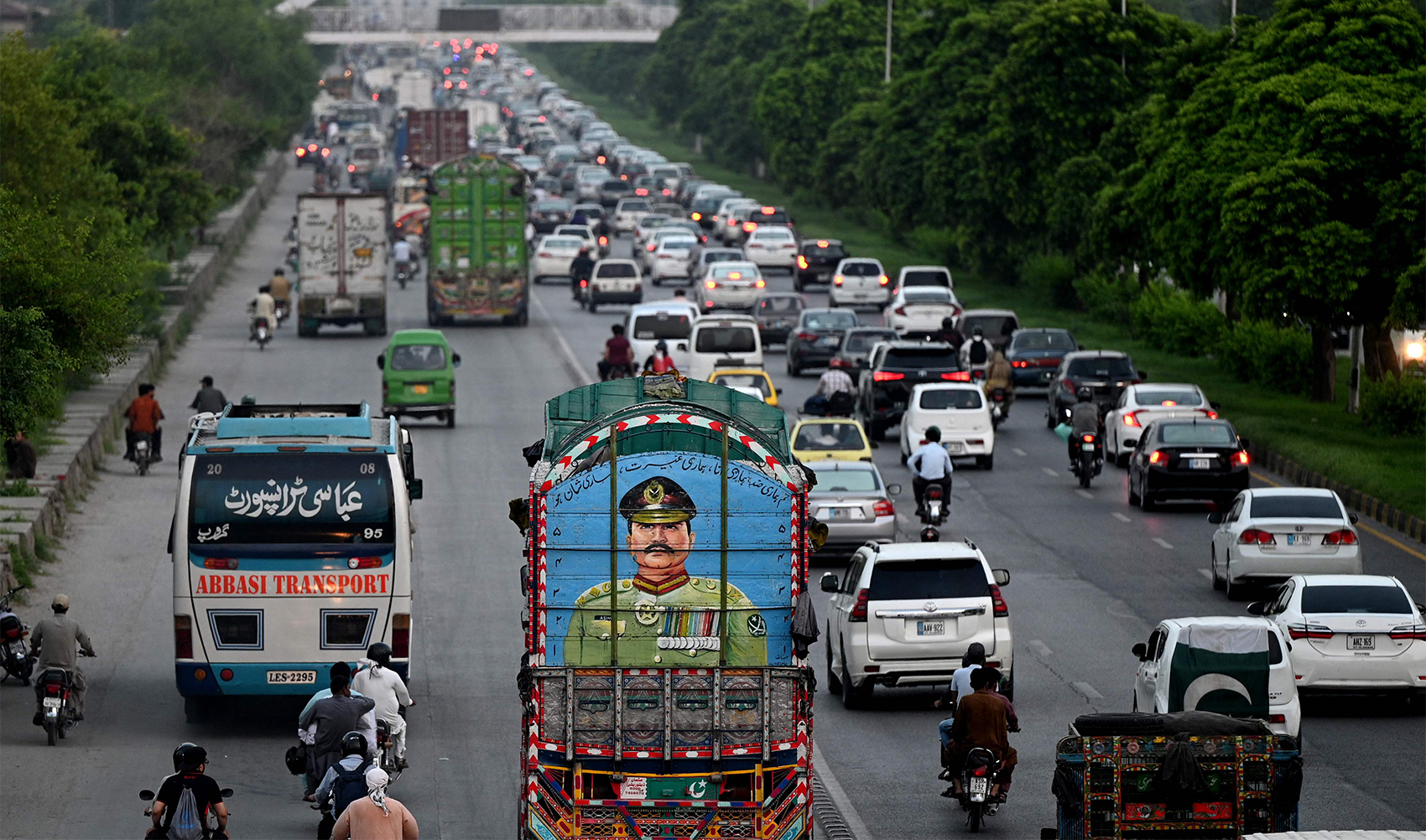 Commuters ride past a truck painted with a portrait of Pakistan's Army Chief General Syed Asim Munir, in Islamabad, Pakistan, on August 16, 2023. (Photo courtesy: AFP)