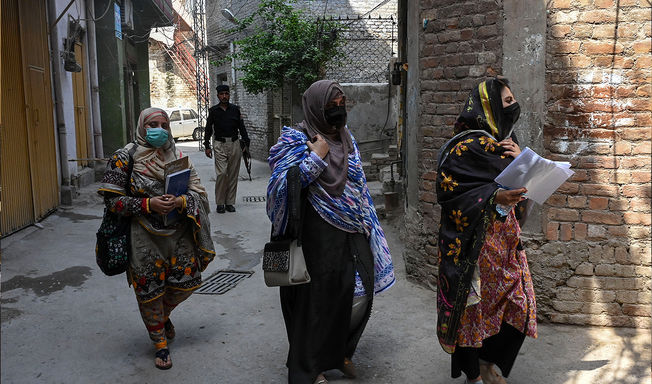 Health workers visit a residential area along with a security personnel during a polio vaccination campaign in Peshawar on May 22, 2023. (AFP/File)