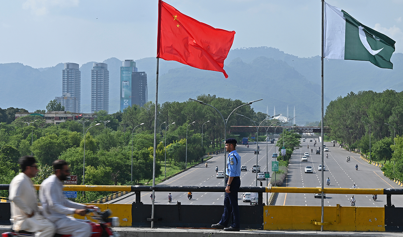 In this file photo, taken on July 30, 2023, a policeman stands guard under the national flags of China and Pakistan along a road, during the visit of Chinese Vice Premier He Lifeng last month, in Islamabad. (AFP/File)