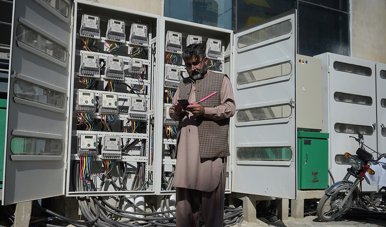 In this file photo, taken on November 7, 2018, a Pakistani employee of the state-run Islamabad Electric Supply Company (IESCO), takes a meter reading with his smartphone at a commercial building in Islamabad. (AFP/File)