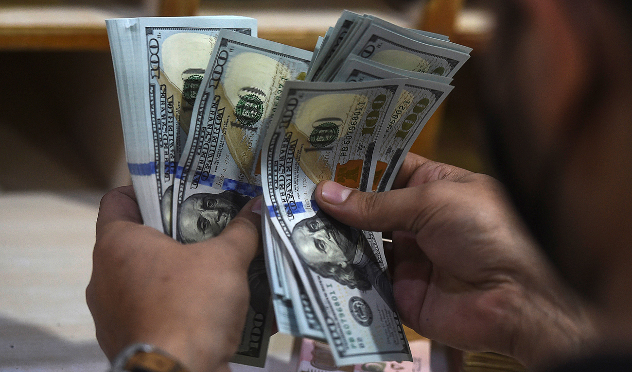 In this picture taken on January 11, 2022, a foreign currency dealer counts US dollar notes at a shop in Karachi. (AFP/File)