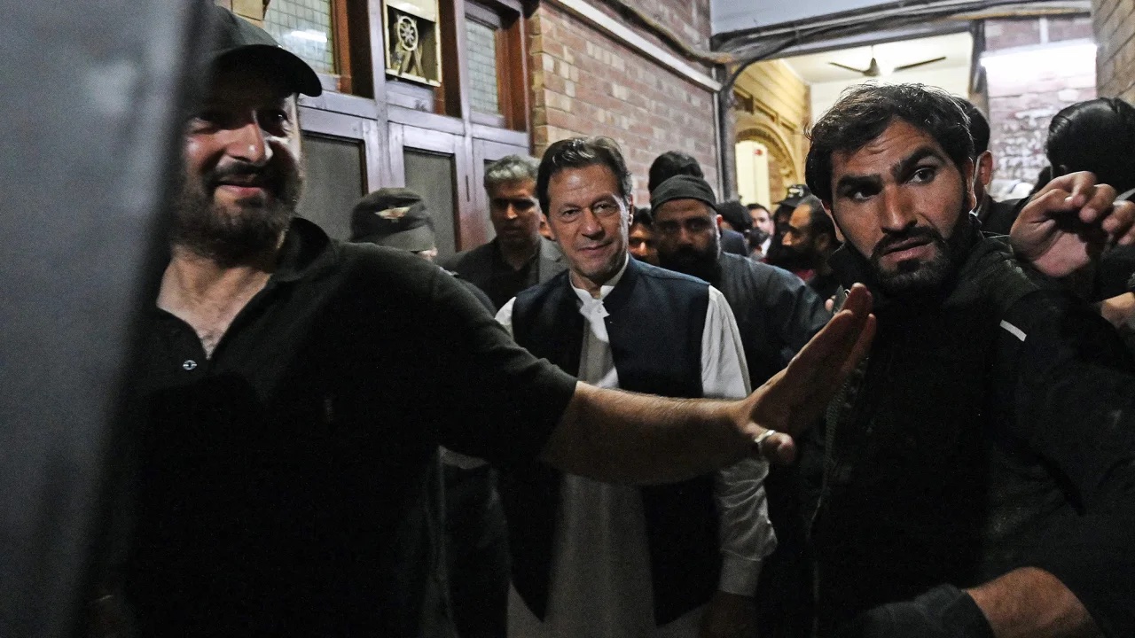 Security personnel use a bullet proof shield to protect former Pakistan's Prime Minister Imran Khan as he leaves after appearing at the high court in Lahore on March 17, 2023. (AFP/File)