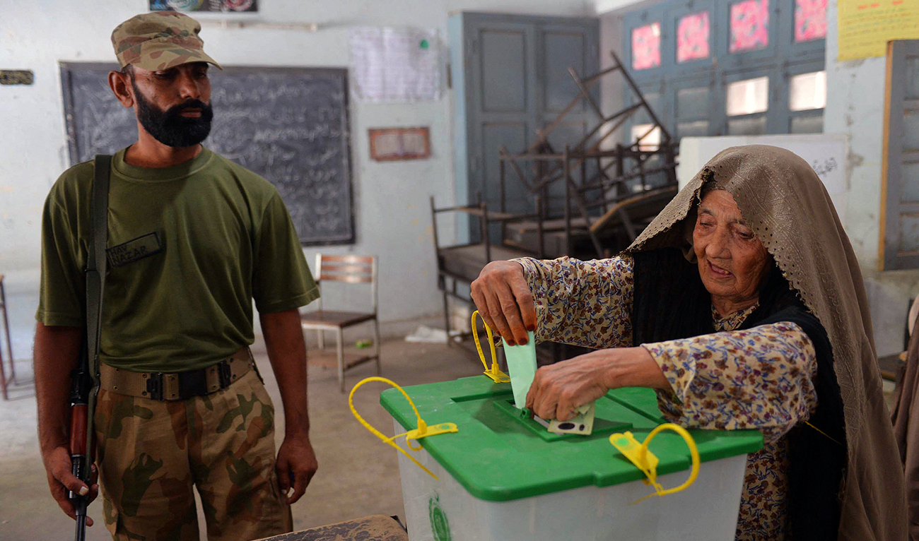 A Pakistani soldier watches a voter cast her ballot during the country's by-election in several constituencies, in Peshawar on August 22, 2013. (AFP/File)