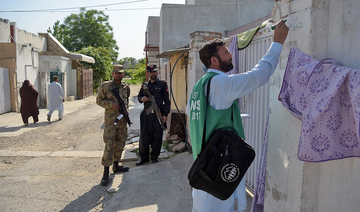 An official from the Pakistan Bureau of Statistics (R) marks a house after collecting information from a resident as Pakistani soldiers stand guard during the second phase of the national census in Islamabad, Pakistan, on April 25, 2017. (AFP/File)
