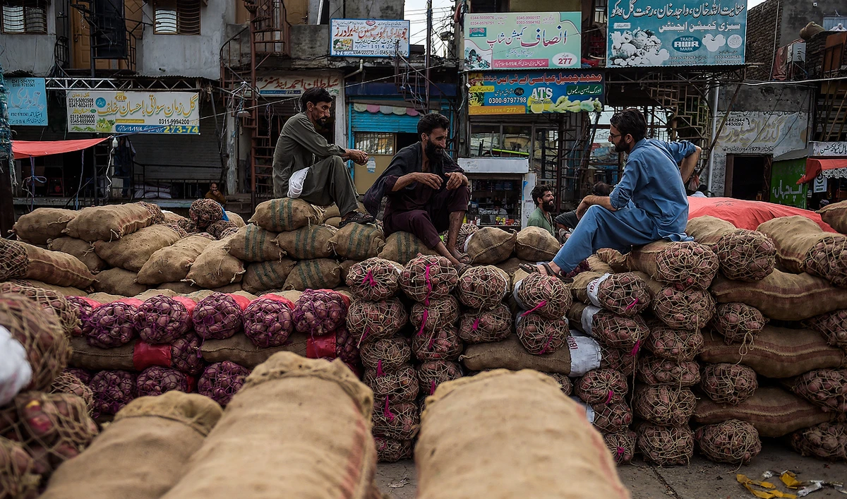 Porters rest on onion and potato bags at a vegetable market on the outskirts of Islamabad on August 19, 2020. (AFP/File)