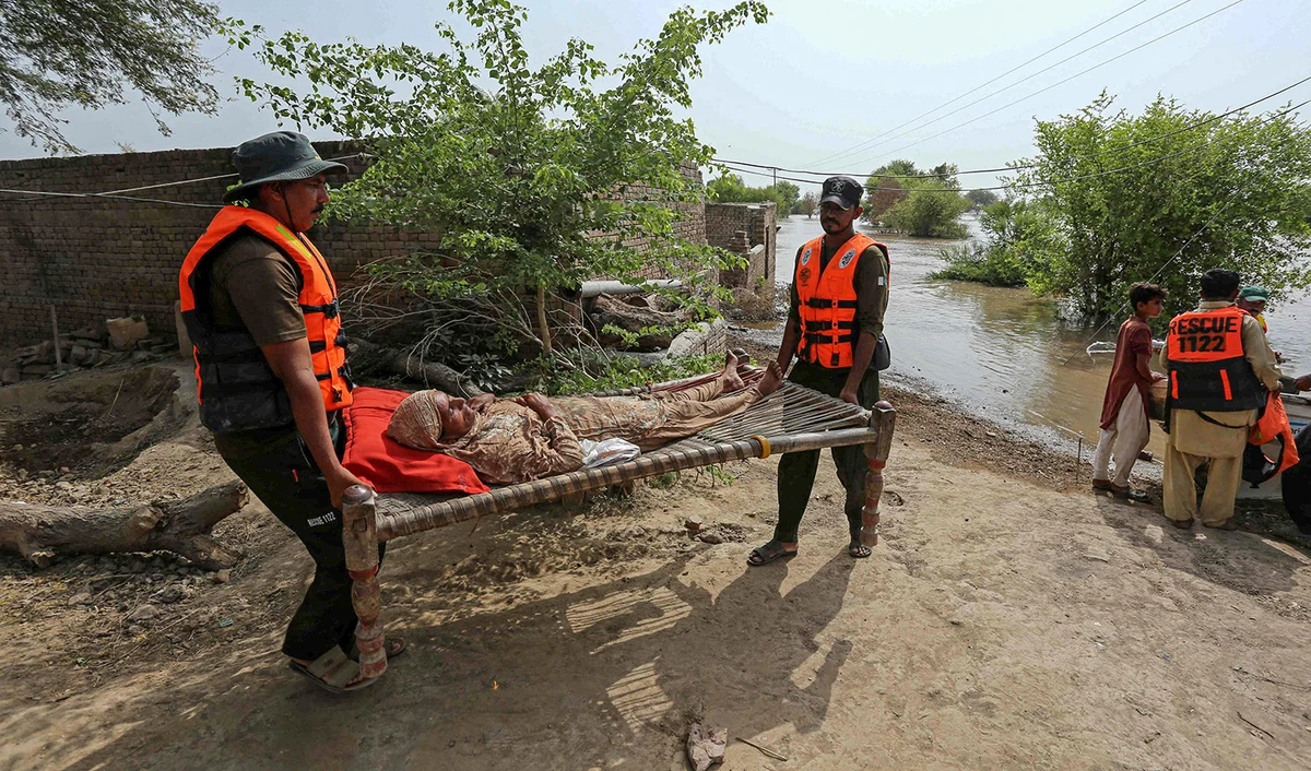 An elderly woman is being evacuated by rescue staff from a flood affected area in Bahawalnagar district of Pakistan's Punjab province on August 26, 2023. (AFP)