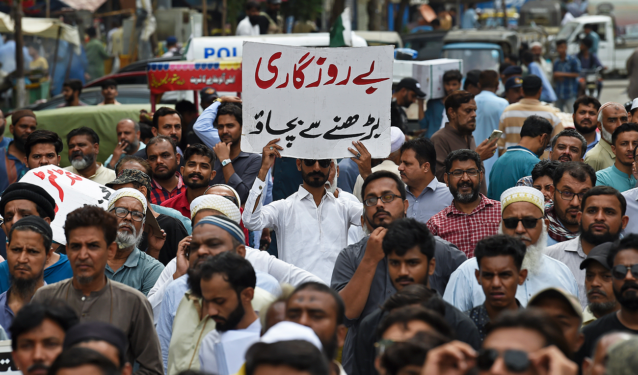 A trader holds a placard reading 'prevent unemployment from rising' during a protest at a street in Karachi on August 23, 2023, against the surge in petrol and electricity prices as Pakistan endures soaring inflation. (AFP/File)