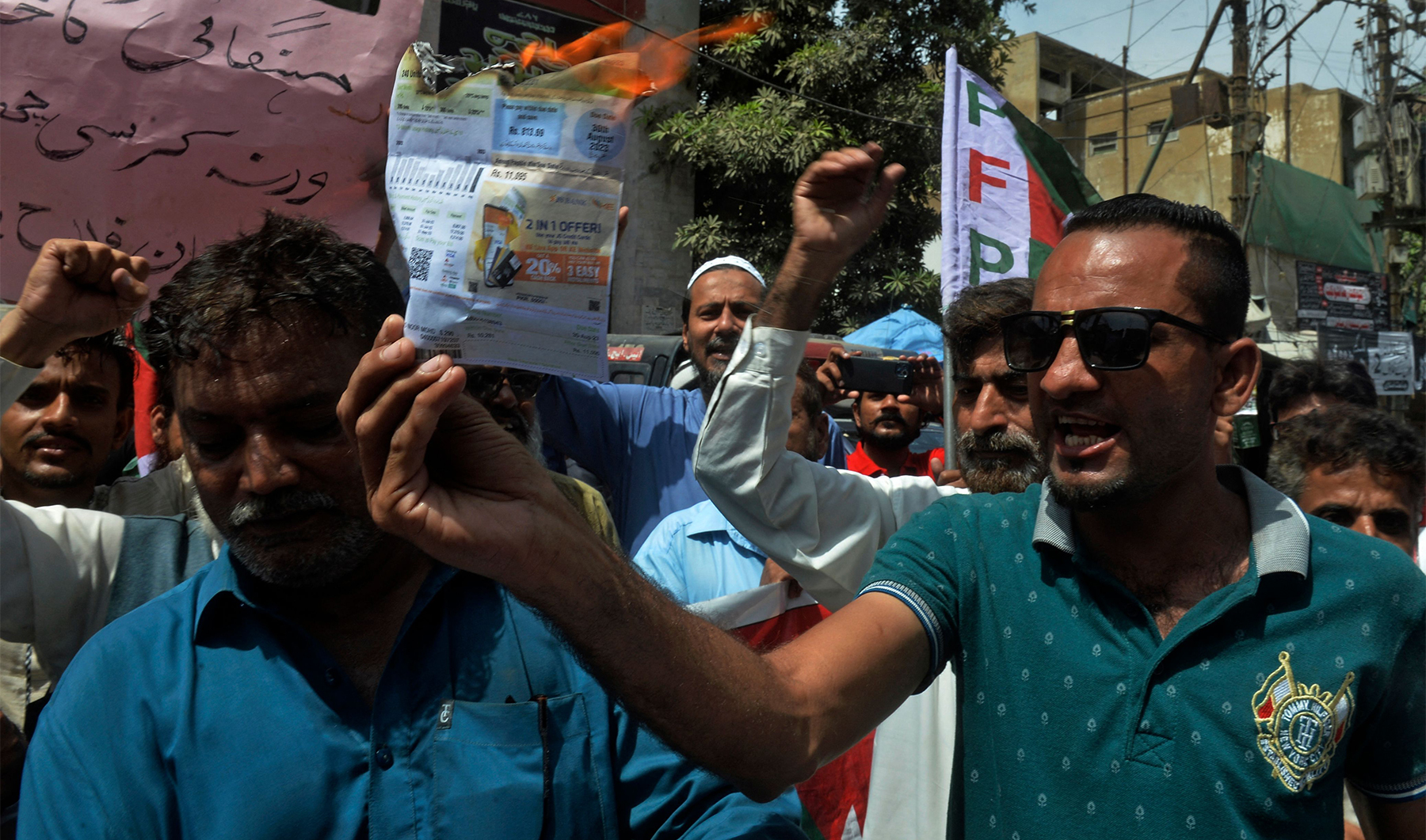 A man burns an electricity bill during a protest against the surge in prices of electricity and fuel in Karachi, Pakistan, on September 1, 2023. (Photo courtesy: AFP)