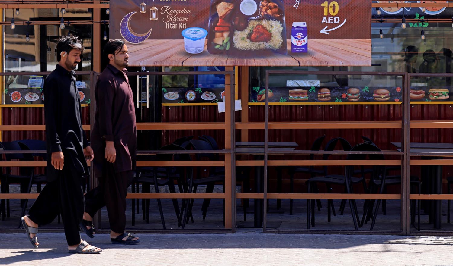 People walk past a Pakistani restaurant offering an iftar meal for two dollars before the start of the holy fasting month of Ramadan, in Dubai on March 22, 2023. (AFP/File)