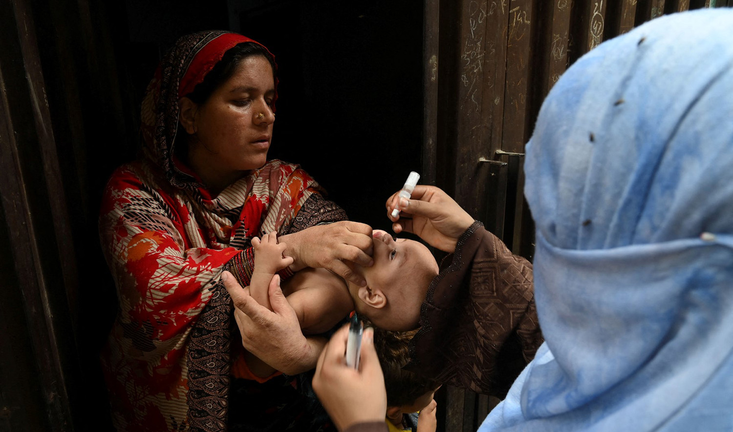 A health worker administers polio vaccine drops to a child during a polio vaccination campaign at a slum area in Lahore, Pakistan, on August 2, 2021. (AFP/File)