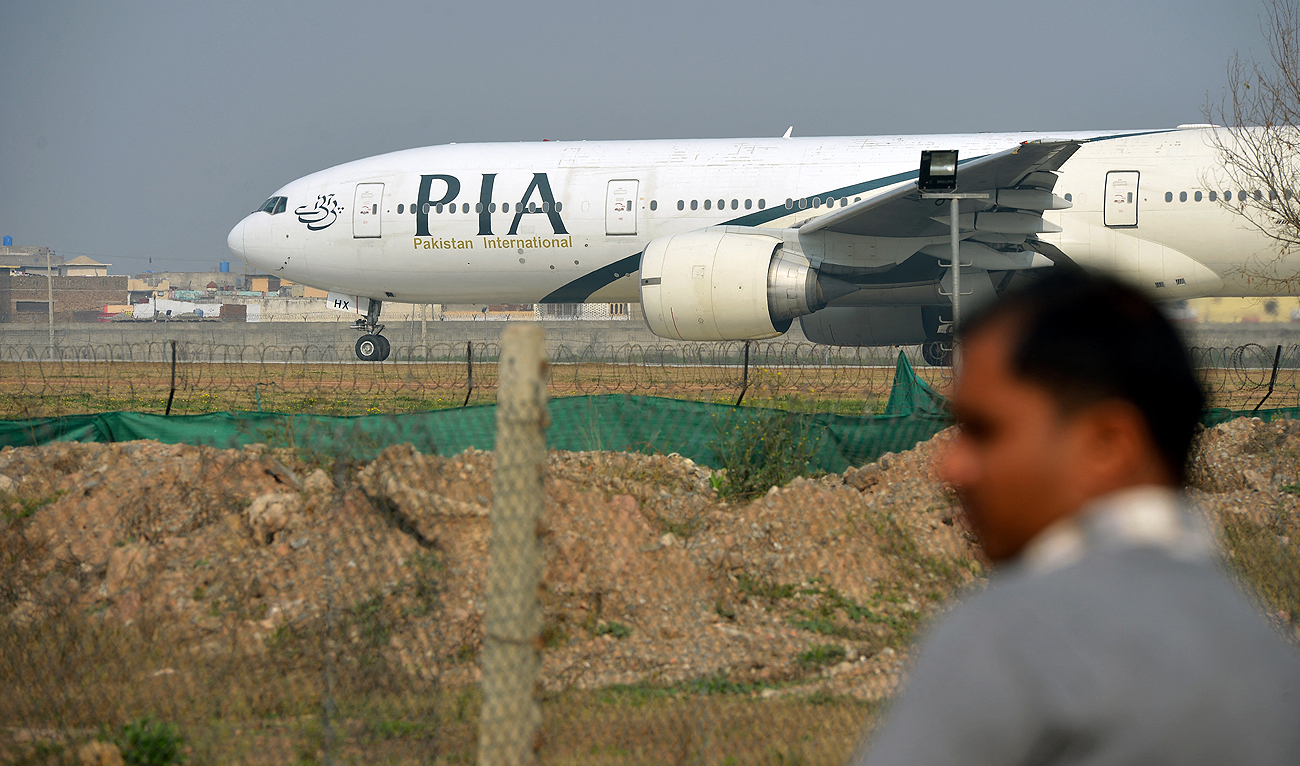 In this file photo, taken on February 8, 2016, a Pakistani man looks on as a Pakistan International Airline (PIA) plane taxis on the runway in Islamabad. (AFP/File)