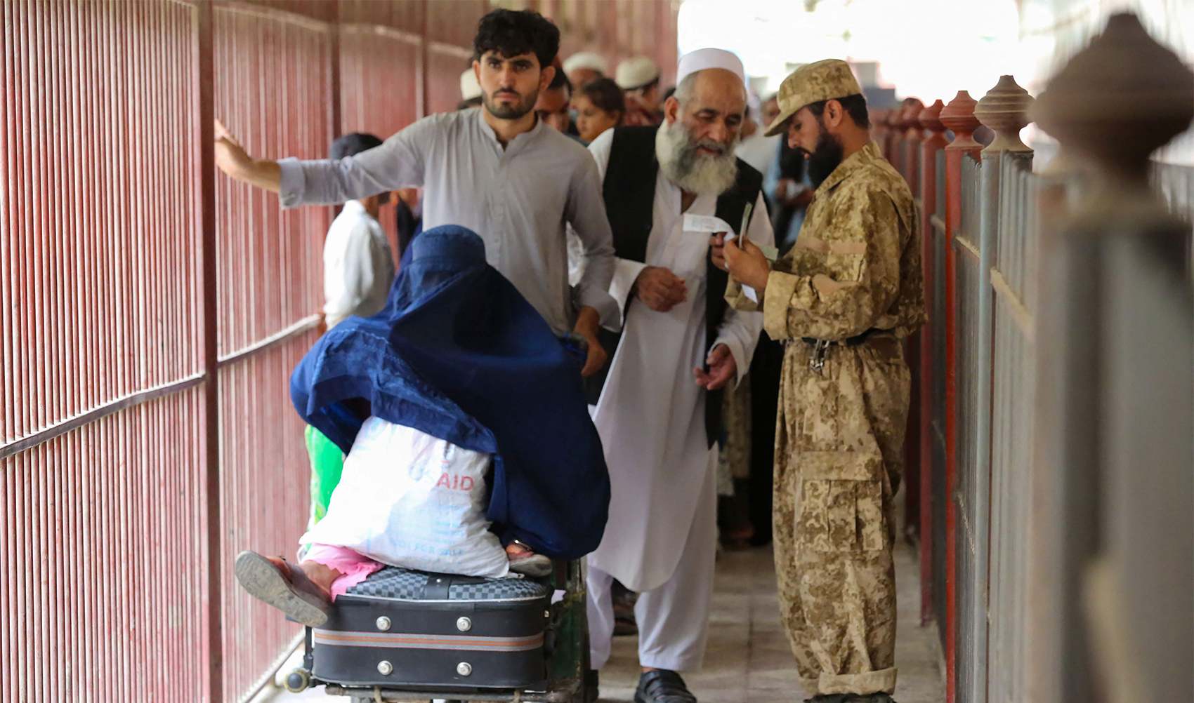 Afghans cross into Pakistan while a security personnel stands guard at the Pakistan-Afghanistan border in Torkham on September 15, 2023. (Photo courtesy: AFP/File)