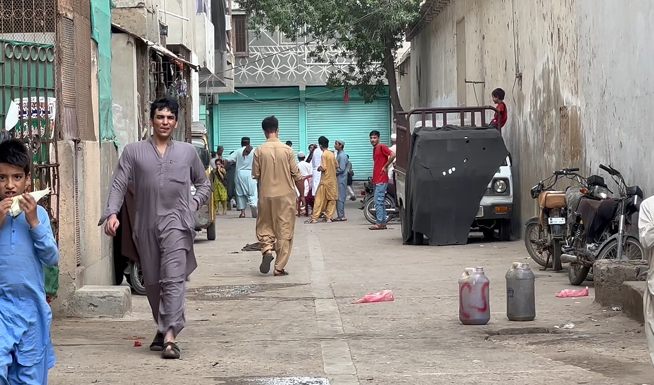A man walks past as children play in a street in the Al-Asif Square neighborhood, mostly populated with Afghan refugees, on the outskirts of Karachi on September 20, 2023. (AN Photo)