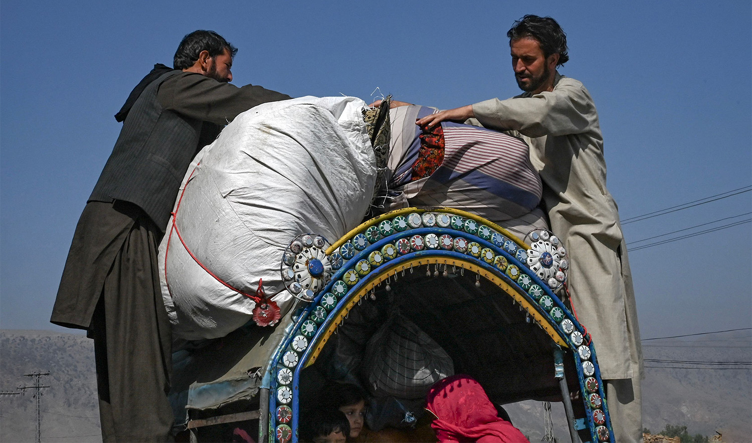 Afghan nationals travelling with their families secure their belongings on a vehicle in Jamrud area of Khyber district, some 30 Km west of Peshawar on October 6, 2023, as they return to Afghanistan following Pakistan's government decision to expel people illegally staying in the country. (AFP)