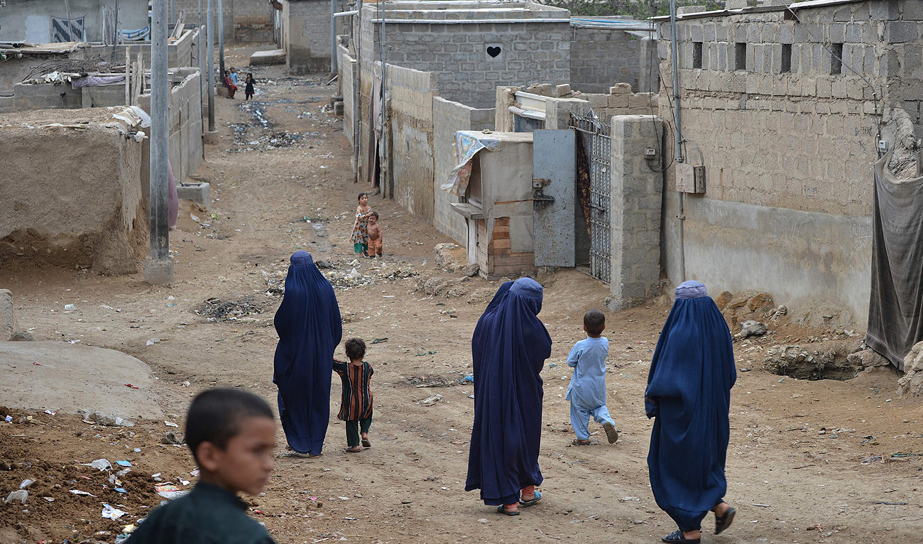 In this photo taken on September 21, 2023, Afghan women walk through an Afghan refugee camp in Karachi. (AFP)