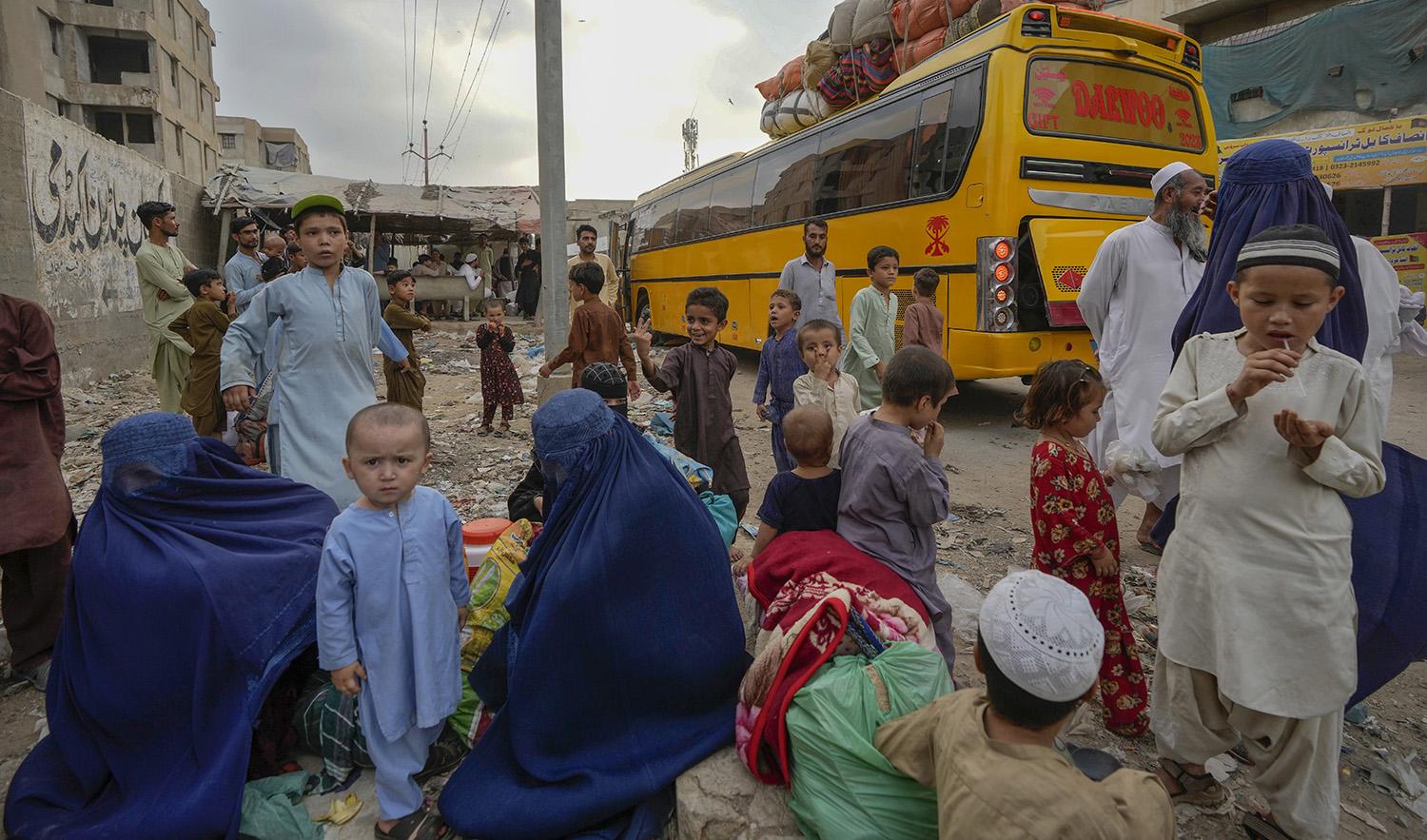 Afghan families wait to board into a bus to depart for their homeland, in Karachi, Pakistan, on October 6, 2023. (AP)