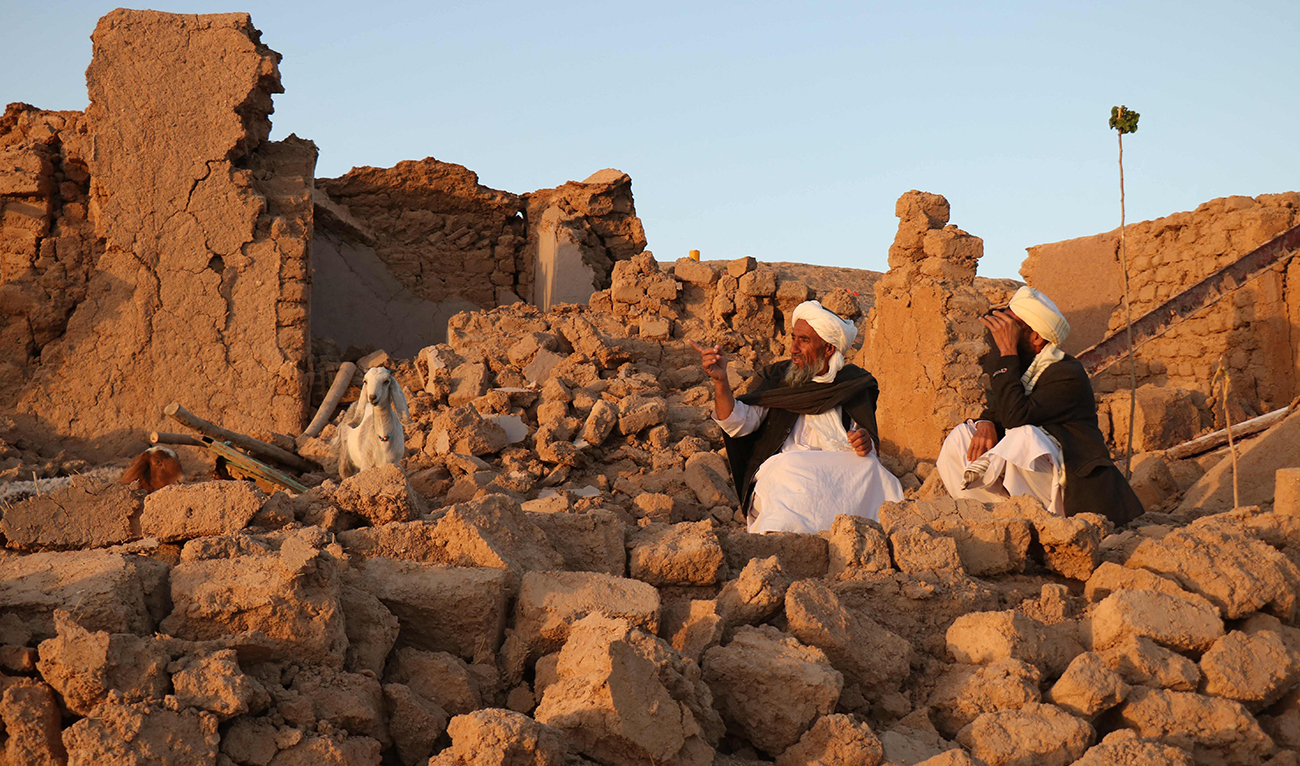 Afghan residents sit at a damaged house after earthquake in Sarbuland village of Zendeh Jan, district of Herat province, on October 7,2023. (AFP)