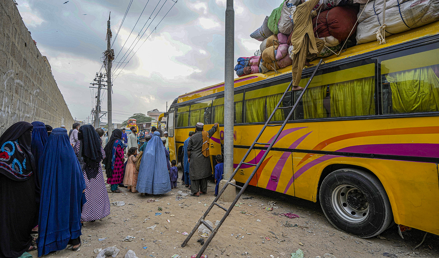 Afghan families board into a bus to depart for their homeland, in Karachi, Pakistan, on October 6, 2023. (AP)