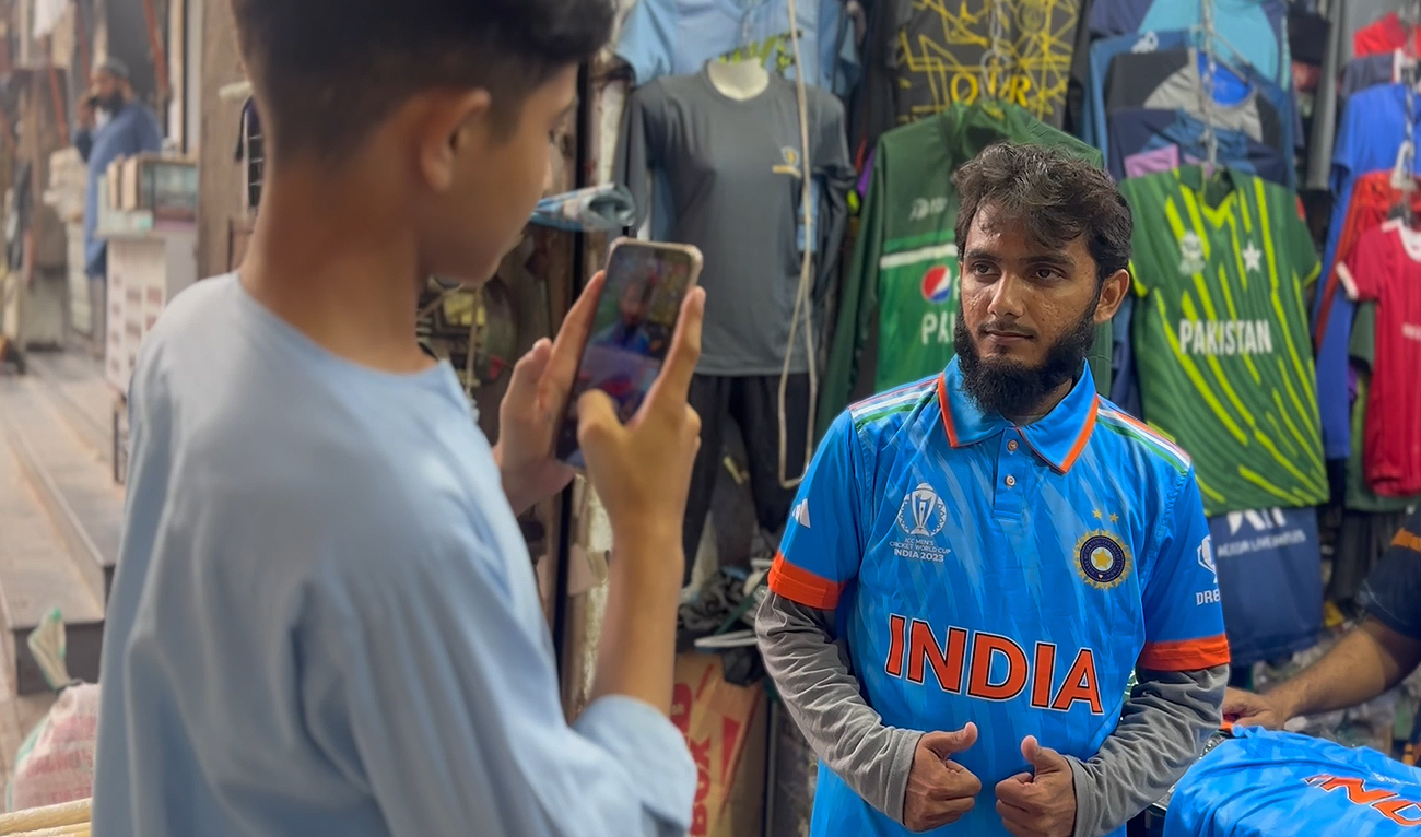 A young boy photographs a man donning an Indian cricket team jersey outside Azeem Sports Shop in Karachi, Pakistan, on October 13, 2023. (AN photo)