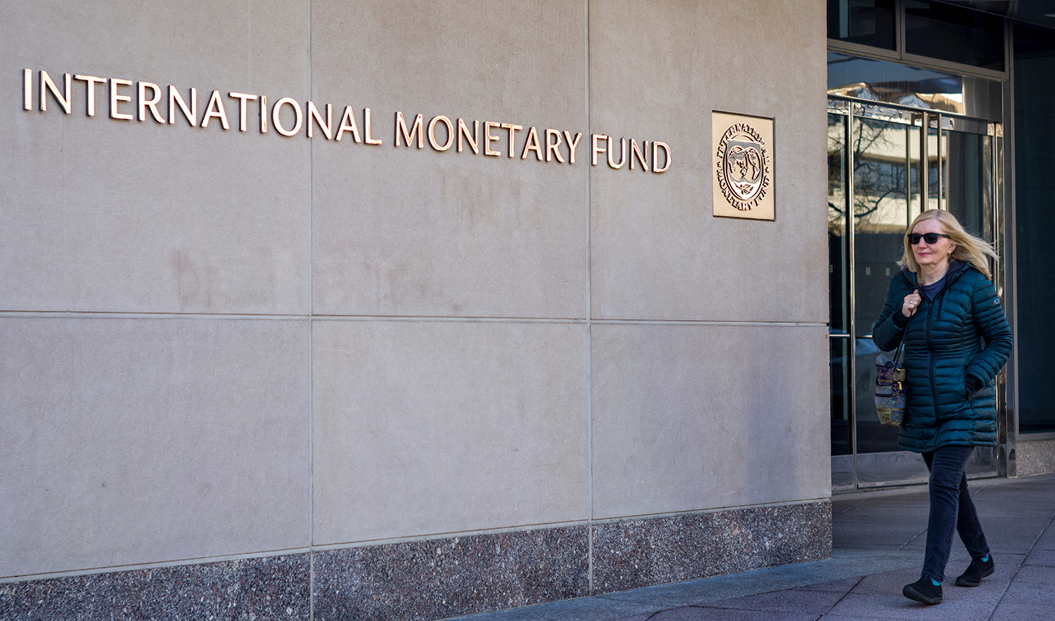 A woman walks past the International Monetary Fund (IMF) headquarters building in Washington, DC on March 11, 2022. (AFP/File)