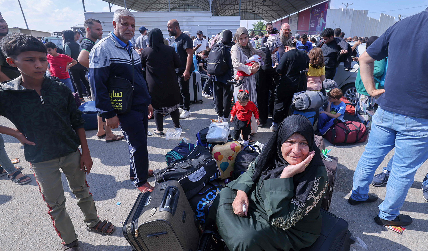 Palestinians, some with foreign passports hoping to cross into Egypt and others waiting for aid wait at the Rafah crossing in the southern Gaza strip, on October 16, 2023. (AFP)