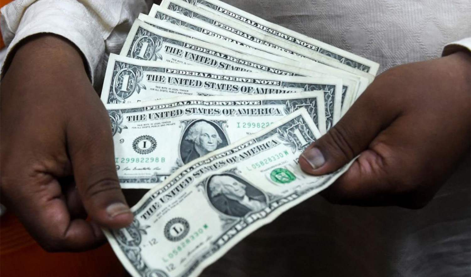 A Pakistani man counts US dollars at the currency exchange place in Lahore, Pakistan on May 16, 2019. (AFP/File)